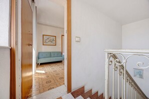 A hallway with a blue sofa, a staircase with white balusters, and patterned floor tiles. - Terrazze Arenella Guest House: Sea View, Wi-Fi, Air Conditioning (Palermo)