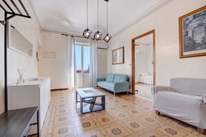 A living room with a sofa, a coffee table, and a white armchair. There is a door leading to a balcony, and a framed picture on the wall. - Terrazze Arenella Guest House: Sea View, Wi-Fi, Air Conditioning (Palermo)