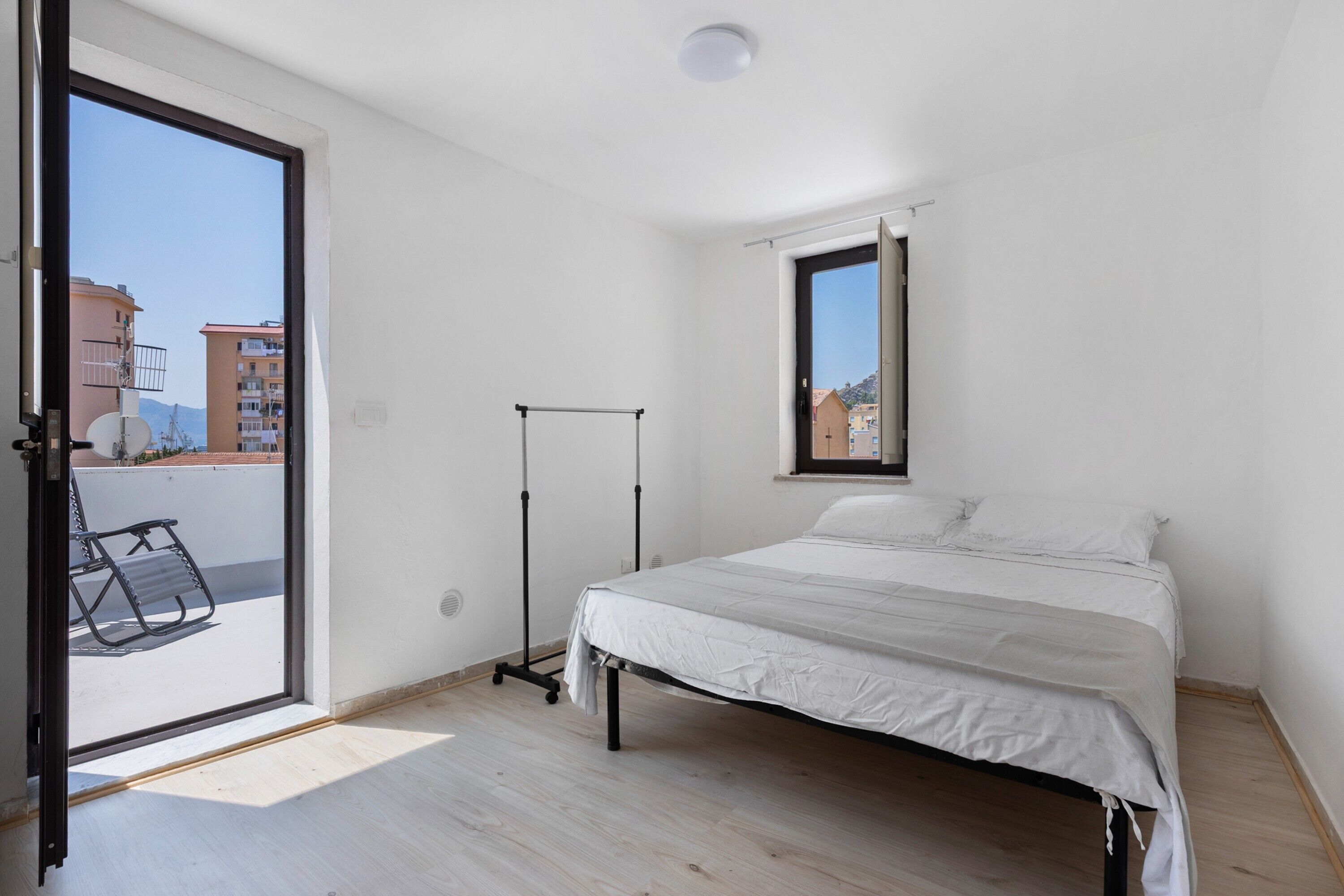 Een slaapkamer met een bed, een raam en een balkon.