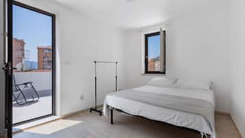 Ein Schlafzimmer mit Bett, Fenster und Balkon.