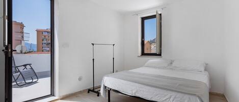 Un dormitorio con cama, ventana y balcón.