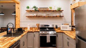 Uma cozinha com armários cinza, um fogão de aço inoxidável, micro-ondas e bancadas de madeira.