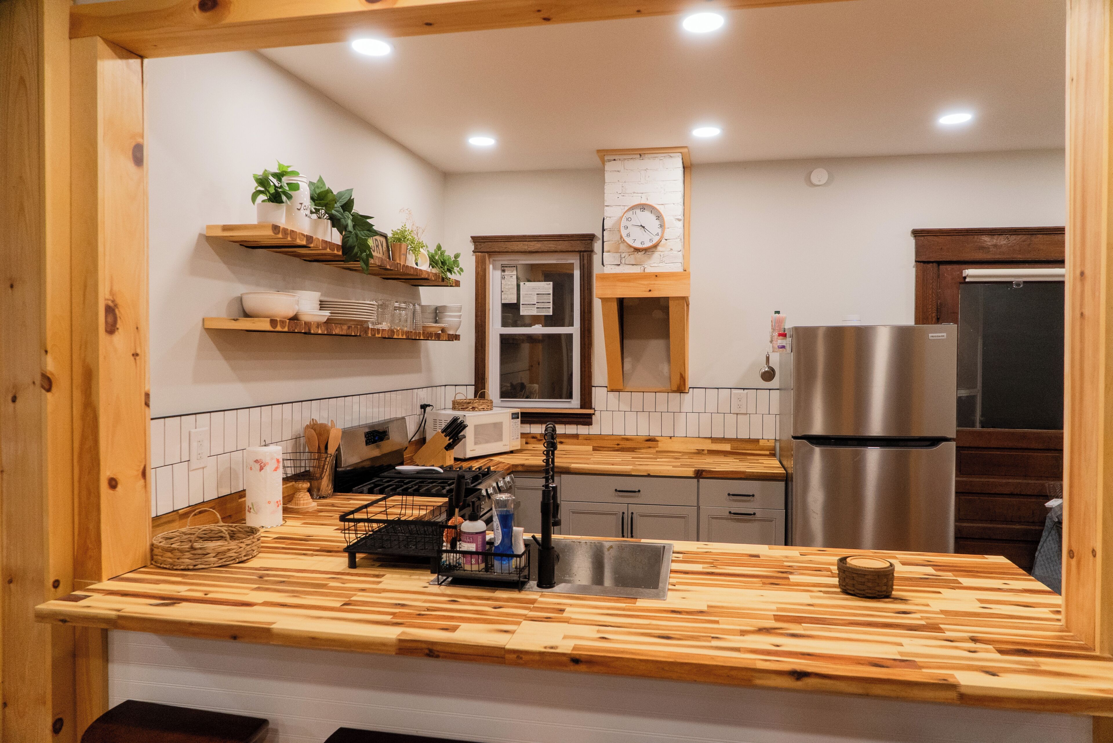 A kitchen with wooden countertops, a stainless steel refrigerator, and a microwave.
