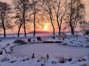 A snow-covered landscape with trees and a frozen body of water during sunset. - Apartment 'Kleines Mehr' with Wi-Fi (Südbrookmerland)