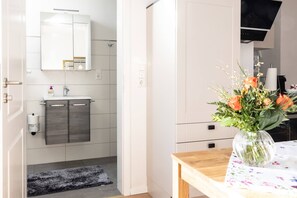 A modern kitchen with a wooden table and a vase of flowers. - Apartment 'Kleines Mehr' with Wi-Fi (Südbrookmerland)