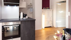 Eine moderne Küche mit Einbaugeräten, einer Kaffeemaschine und einem Essbereich mit einem Glastisch.