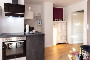 A modern kitchen with built-in appliances, a coffee machine, and a dining area with a glass table. - Apartment 'Kleines Mehr' with Wi-Fi (Südbrookmerland)
