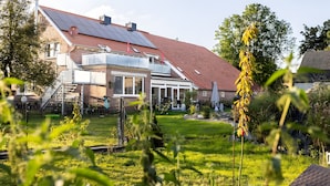 Ein Wohnhaus mit geneigtem Dach, Solaranlagen, umzäuntem Garten und einem Garten.