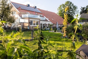 A residential property with a sloped roof, solar panels, a fenced yard, and a garden. - Apartment 'Kleines Mehr' with Wi-Fi (Südbrookmerland)