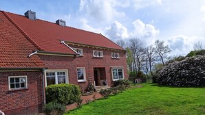Ein zweistöckiges Backsteinhaus mit rotem Ziegeldach, einer Veranda und einem gepflegten Rasen.