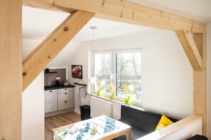Een moderne keuken met witte kasten, een zwart aanrecht en een raam met uitzicht op bomen.