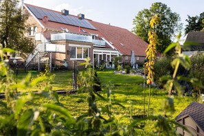 Een woonhuis met een schuin dak, zonnepanelen, een omheinde tuin en een tuin.
