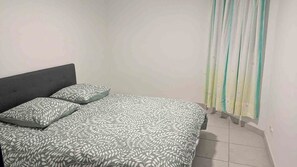 Un dormitorio con cama, almohadas y cortinas.