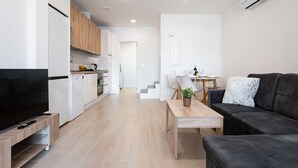 Et moderne opholdsrum med et køkken, spiseplads og en sofa.