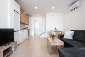 A modern living space with a kitchen, dining area, and a sofa. - MalagaSuite Urban Beach A (Torremolinos)