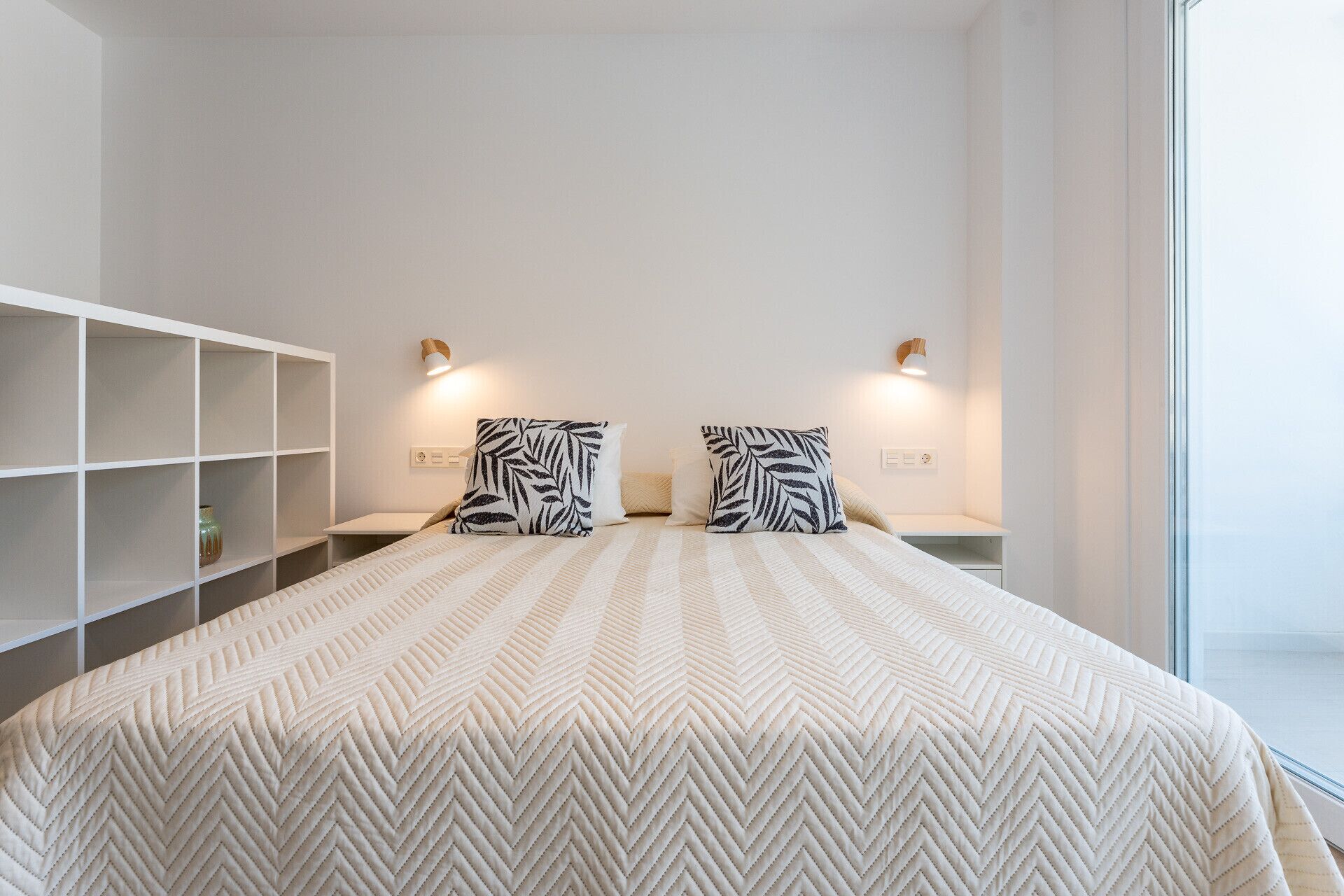 Una camera d'albergo con un letto grande, due comodini, un armadio bianco e una finestra.