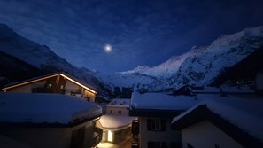 A snow-covered mountain village at night with a visible moon. - High-quality, stylish furnishings | Mountain views (Saas-Fee)