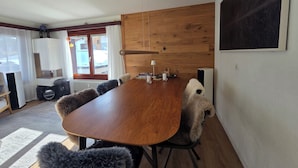 Comedor con una mesa y sillas de madera, un ventilador de techo y vistas a través de una ventana.