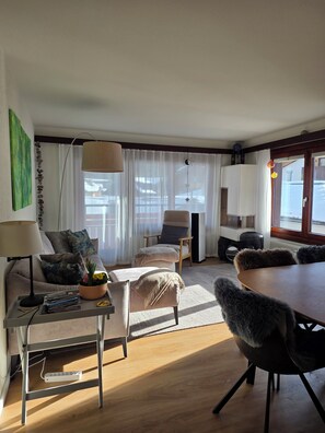 A modern living room with a sofa, armchair, dining table, and a coffee table. There is a lamp, a potted plant, and a decorative hanging. - High-quality, stylish furnishings | Mountain views (Saas-Fee)