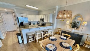 Una cocina moderna con armarios blancos, una isla central y taburetes de bar.