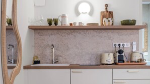A modern kitchen with white cabinets, a wooden countertop, and a large mirror. - Theava Collection -Citadelle- St Tropez (Saint-Tropez)