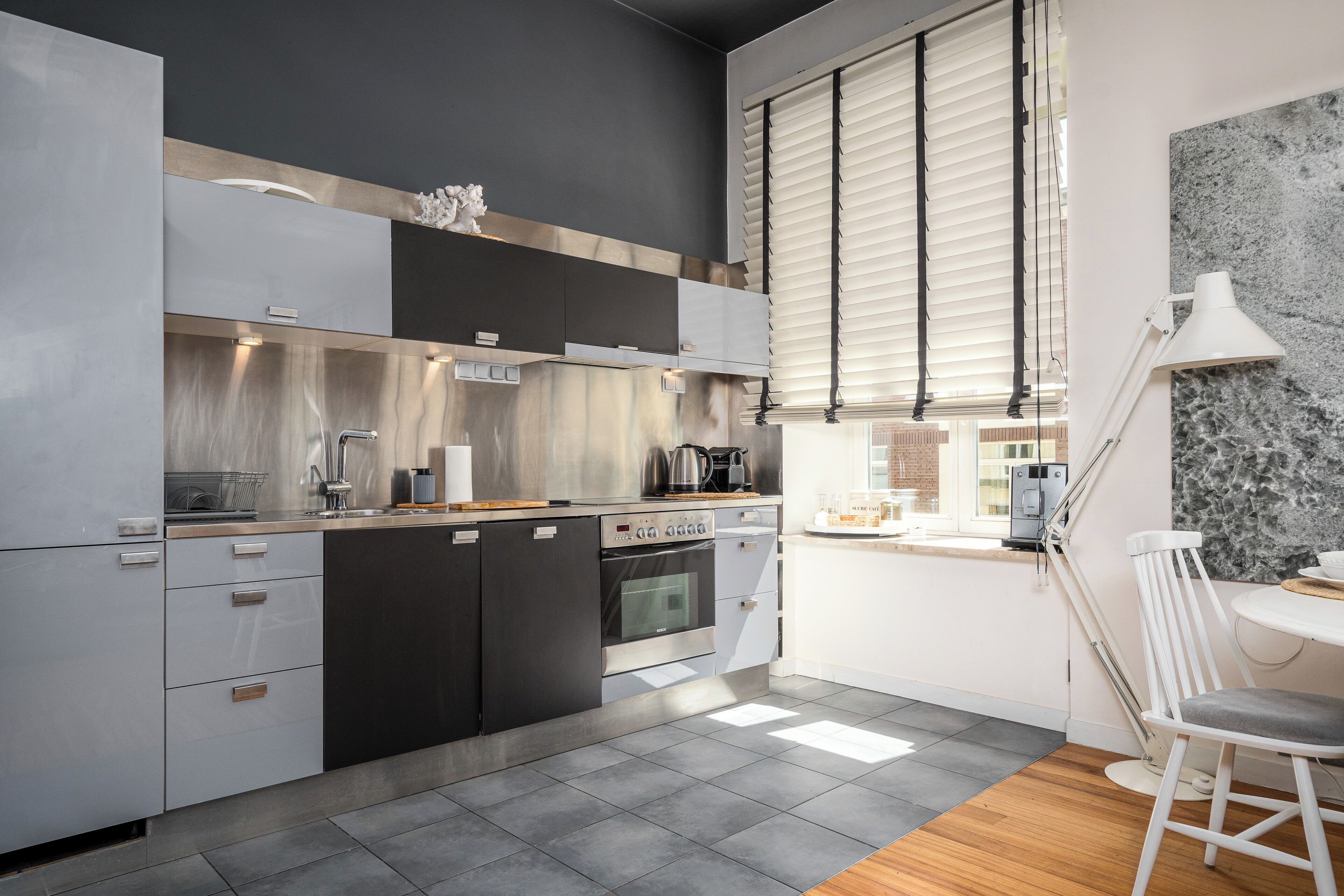 Una cocina moderna con electrodomésticos de acero inoxidable, horno empotrado y cafetera.