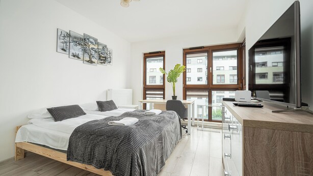 Ett modernt sovrum med en säng, ett skrivbord och stora fönster.