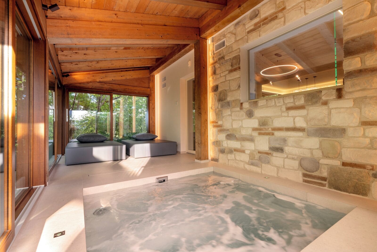 A spa area with a stone wall, a glass enclosure, and a hot tub.