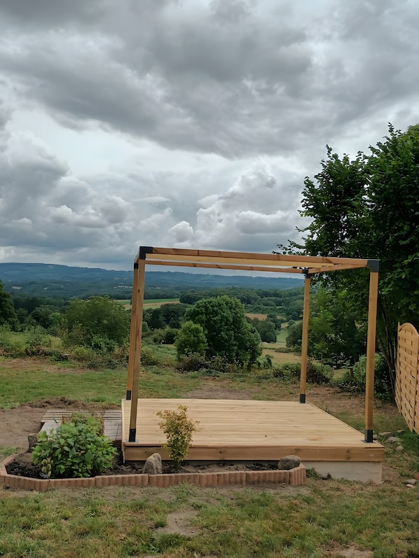 Une pergola en bois offrant une vue sur un paysage rural.
