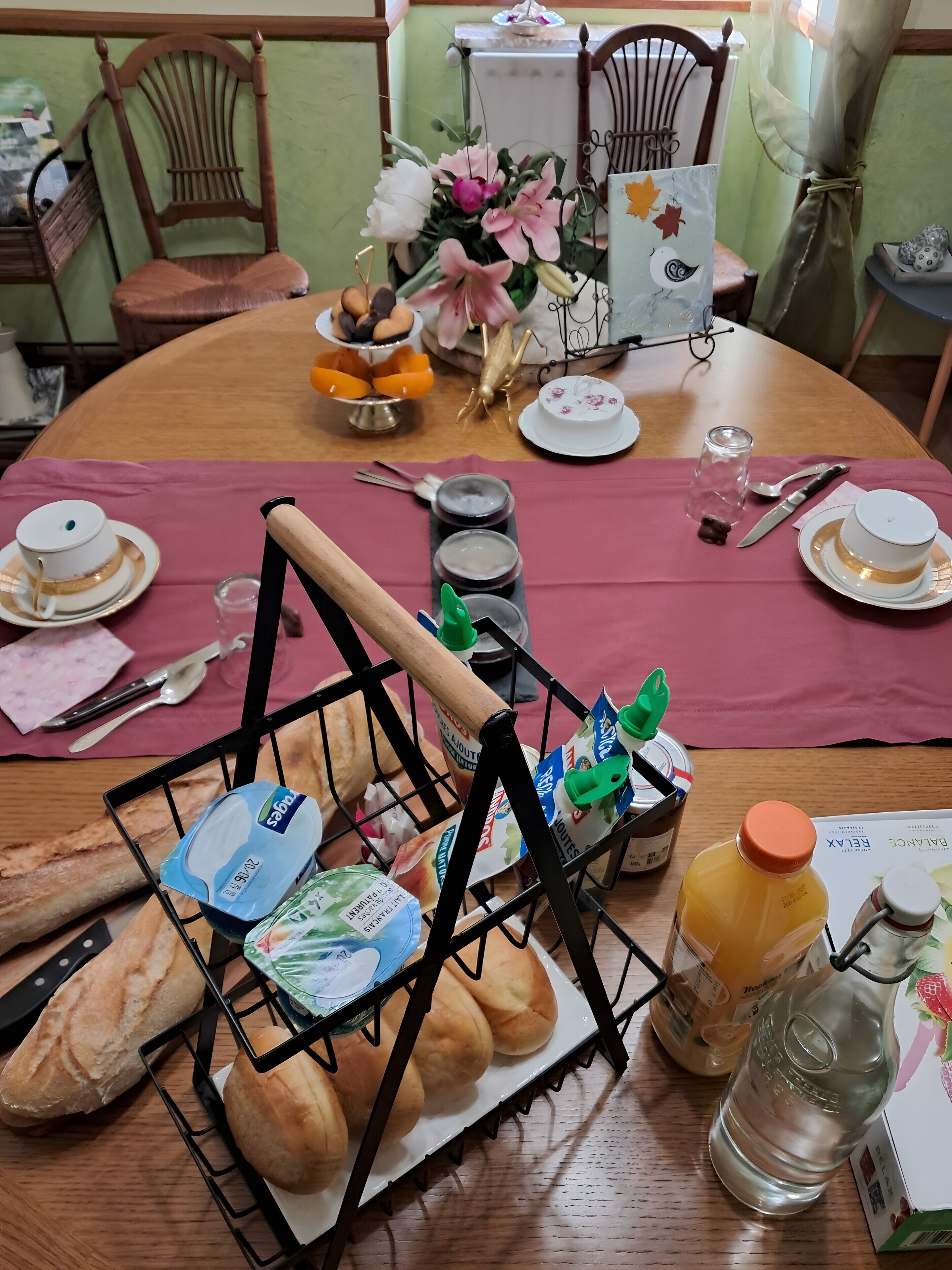 A dining table set with a variety of food items, including bread, pastries, and a fruit display.