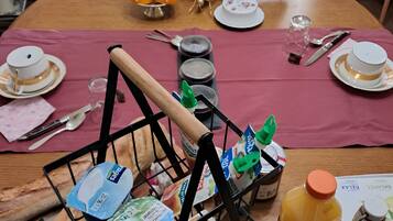 A dining table set with a variety of food items, including bread, pastries, and a fruit display.
