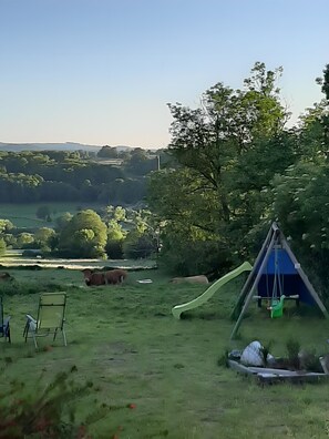 Un espace extérieur verdoyant avec une balançoire, un toboggan et une chaise.