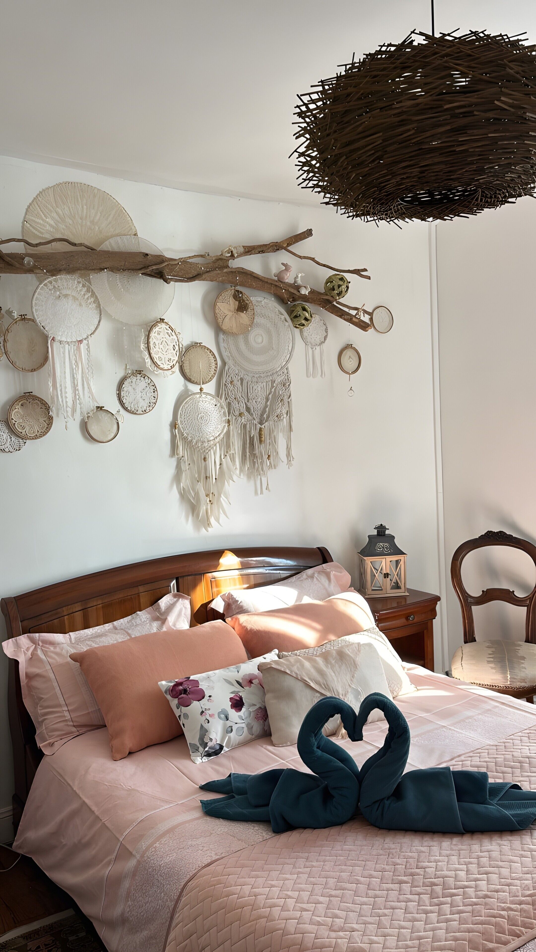 Een slaapkamer met een bed, kussens, een hangende dromenvanger en een lantaarn.