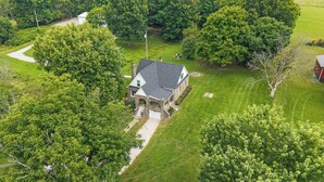 A stone house with a sloped roof, surrounded by lush greenery and a well-maintained lawn. - 3BR Stone Farm House, Parking, Grill, Laundry (Florence)