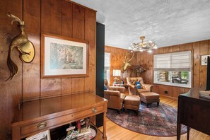 A room with wooden paneling, a large framed picture, a chandelier, leather armchairs, and a piano. - 3BR Stone Farm House, Parking, Grill, Laundry (Florence)