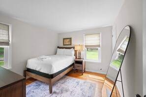 A bedroom with a bed, bedside table, lamp, and a mirror. - 3BR Stone Farm House, Parking, Grill, Laundry (Florence)