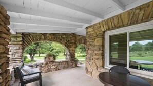 A covered patio area with stone walls, a table, and a bench. - 3BR Stone Farm House, Parking, Grill, Laundry (Florence)