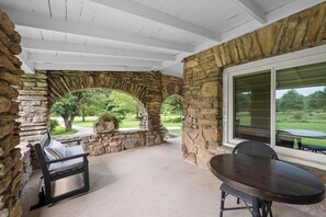 A covered patio area with stone walls, a table, and a bench. - 3BR Stone Farm House, Parking, Grill, Laundry (Florence)