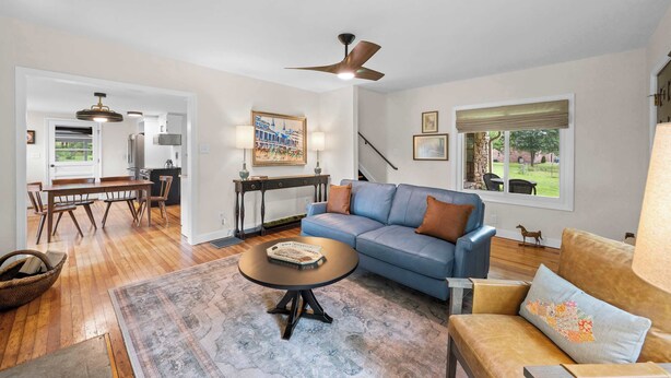 A living room with a blue sofa, a coffee table, and a dining area with a wooden table and chairs. - 3BR Stone Farm House, Parking, Grill, Laundry (Florence)