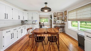 A kitchen with white cabinets, a wooden dining table, and chairs. - 3BR Stone Farm House, Parking, Grill, Laundry (Florence)
