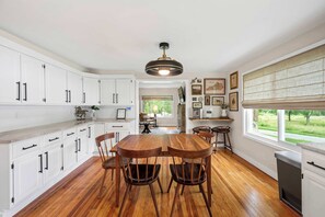 A kitchen with white cabinets, a wooden dining table, and chairs. - 3BR Stone Farm House, Parking, Grill, Laundry (Florence)