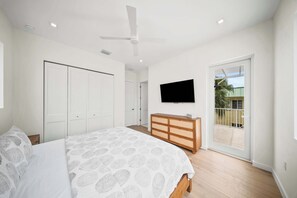 A bedroom with a bed, a dresser, a television, and a balcony. - Luxury 5BD/6BTH+ Bonus cabana room|Pool|Dockage X2 (Marathon)