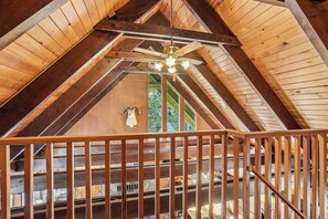 A wooden interior with a sloped ceiling, a mounted animal head, and a view of the outdoors through windows.