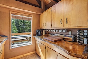 A wooden kitchen with a built-in window, wooden cabinets, a coffee maker, a toaster, and spice jars.