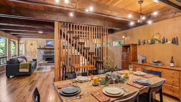 A dining area with a wooden table set for four, a fireplace, and a view of the outdoors.