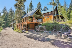 A cabin with a wooden deck, a covered porch, and a stone wall.