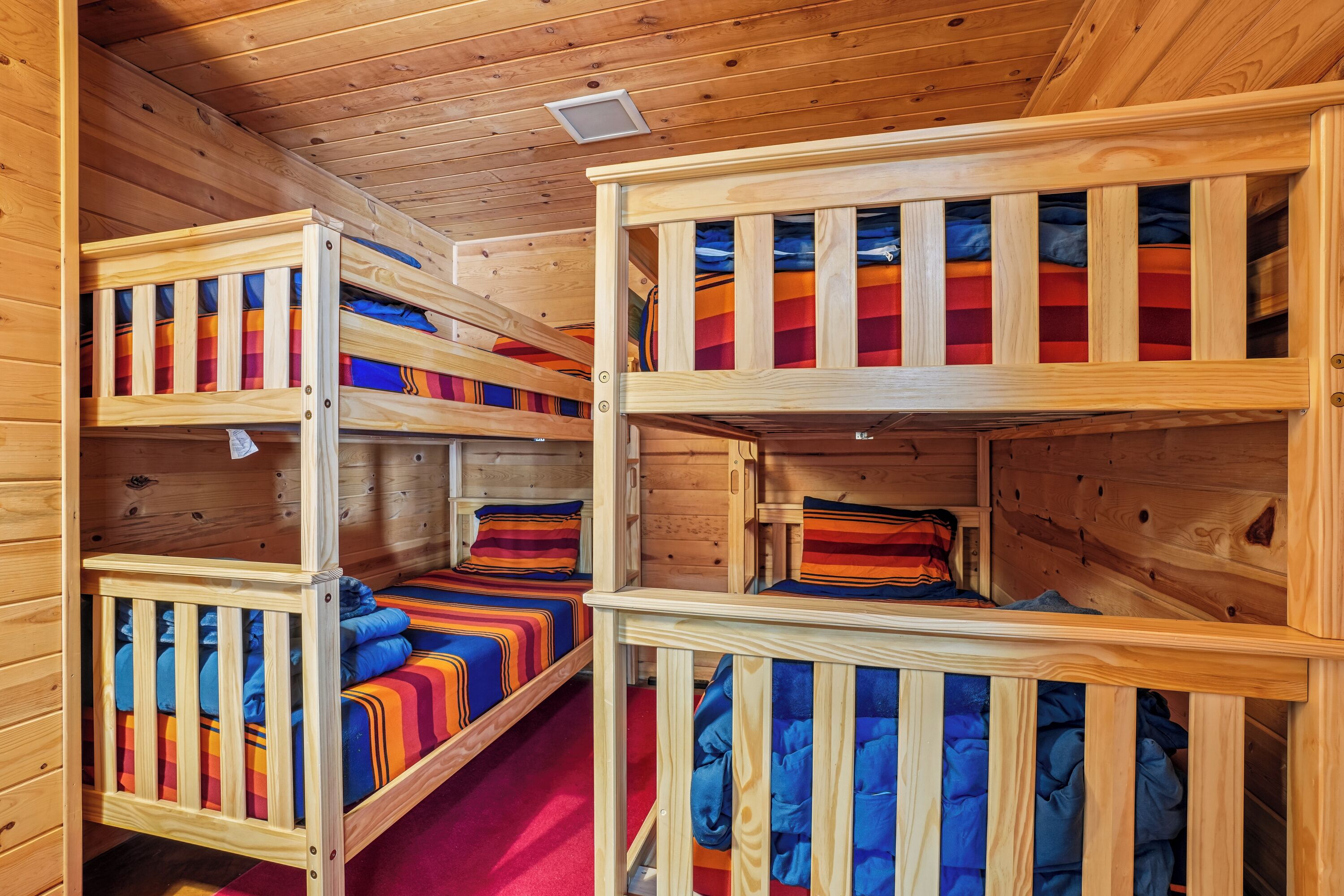 A cabin with bunk beds, wooden walls, and a ceiling light.