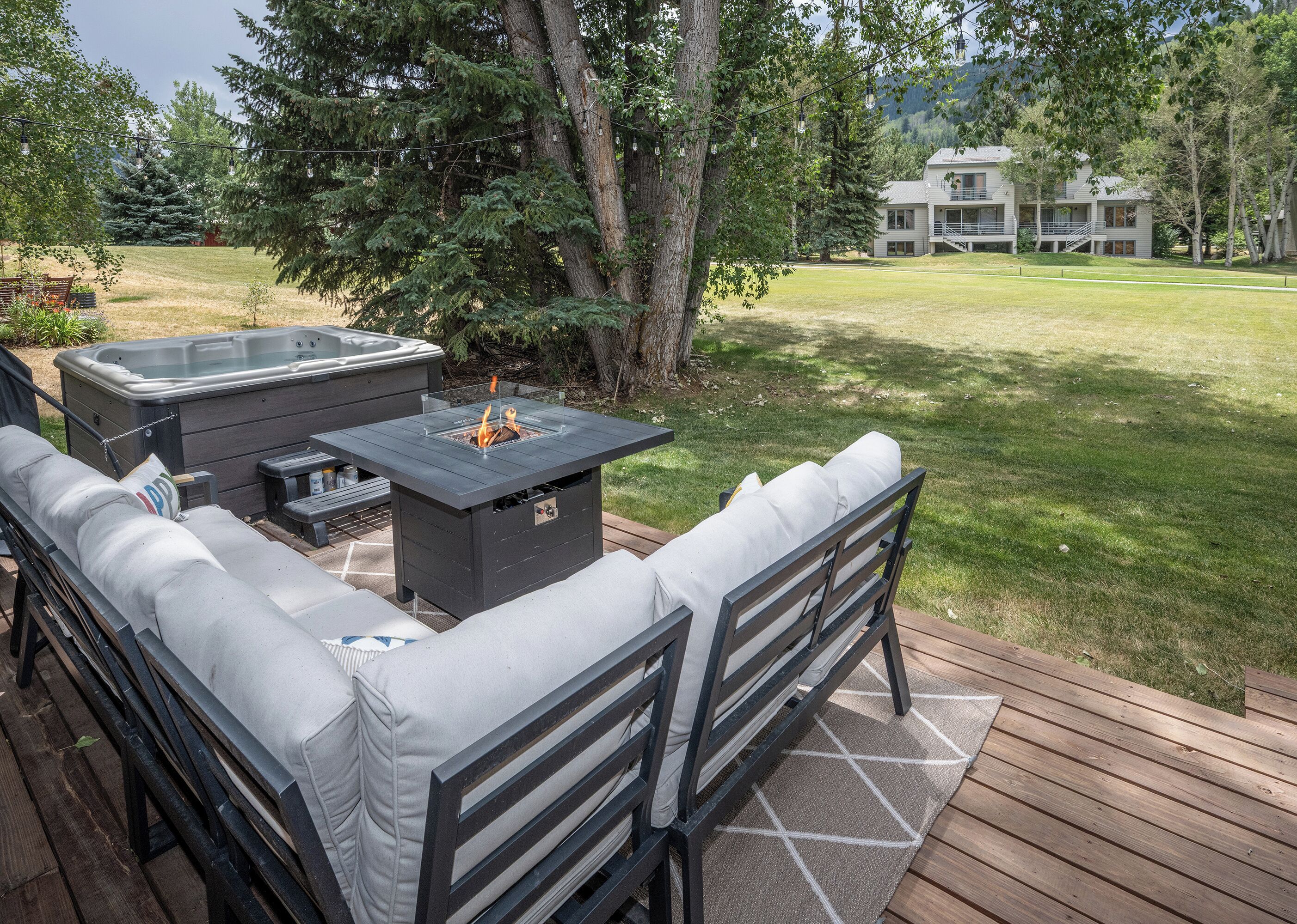 An outdoor deck with a fire pit, seating, and a hot tub.