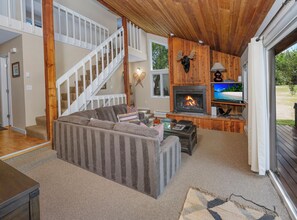 Ein Wohnzimmer mit Kamin, einer Couch, einem Fernseher und einer Treppe.