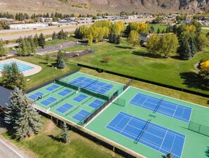 Ein Tennisplatzkomplex mit mehreren Plätzen, umgeben von Grünflächen und Bäumen.